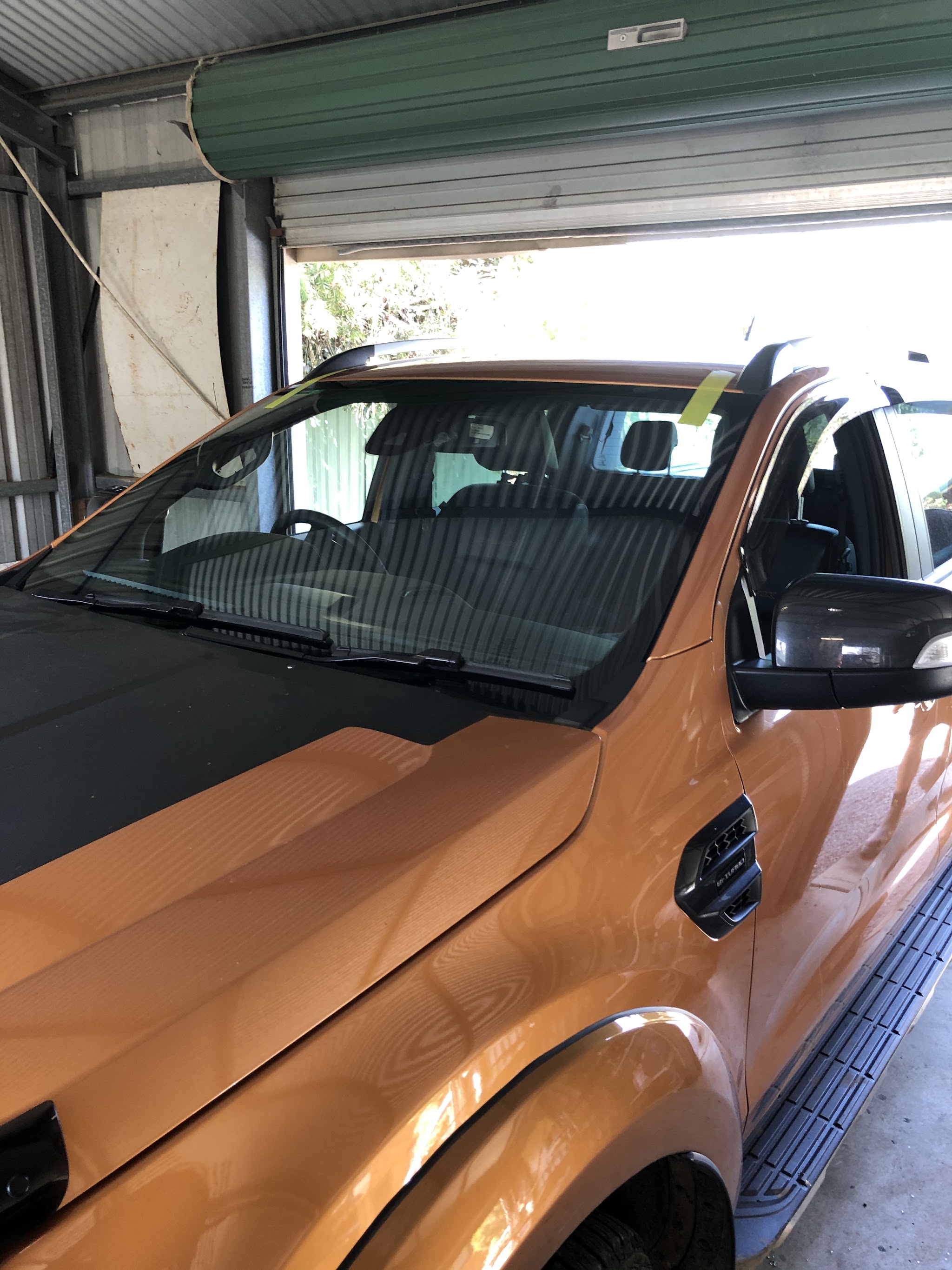 A newly fitted windscreen on a ute in the Cascade Autoglass workshop bay, retention tape still in place